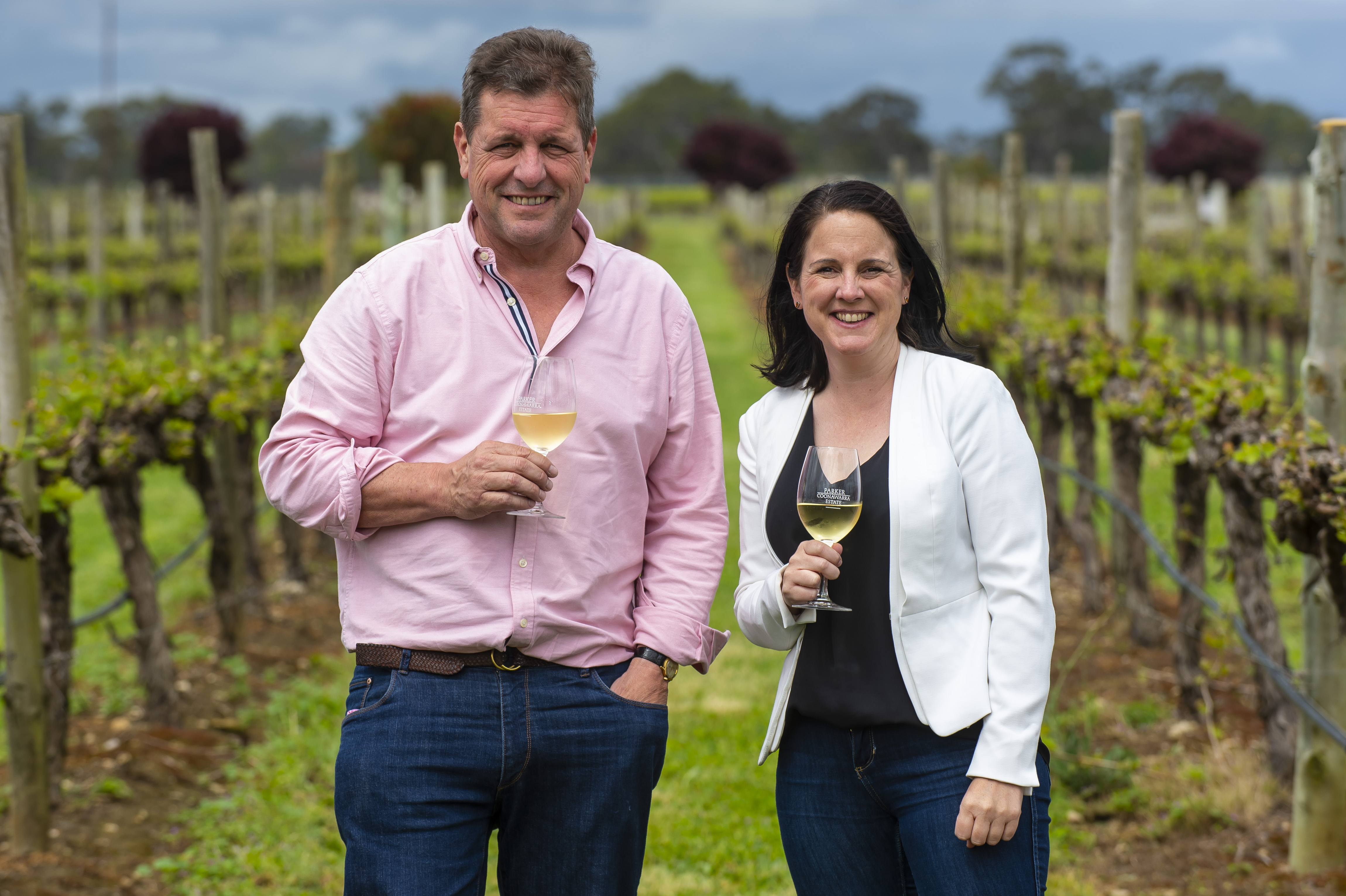 Andrew Hardy and Keeda Zilm in the vineyard holding wine glasses. 